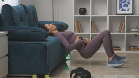 exercise-for-abdominal-muscles-young-woman-is-lifting-hips-up-leaning-on-couch-holding-weight-on-belly-training-at-home-fitness-and-wellness